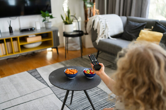 Girl using TV remote control in living room at home