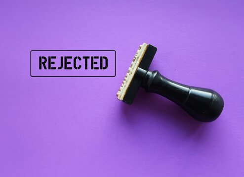Rubber stamp with stamp words REJECTED on purple background, means refuse to agree to request, not given approval or acceptance to work or offer