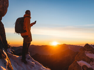 Hiker photographing mountains at sunrise