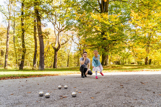 Girl playing boules with father in park