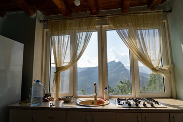 Kitchen countertop with sink and gas stove with window and view of mountain top of Gunib plateau in Dagestan