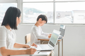 学校・塾のICT教育でパソコンを使って勉強するアジア人の子供（ICT教育・授業・生徒）
