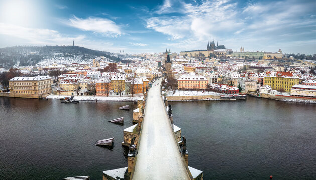 Panoramic winter view over the famous Charles Bridge in Prague, Czech Republic, to the snow covered skyline of the old town and Castle