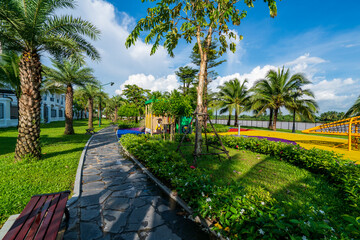 Obraz premium Public green park with modern blocks of flats and blue sky with white clouds in Vietnam