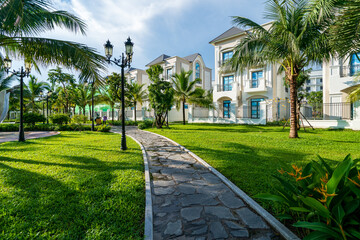 Obraz premium Public green park with modern blocks of flats and blue sky with white clouds in Vietnam