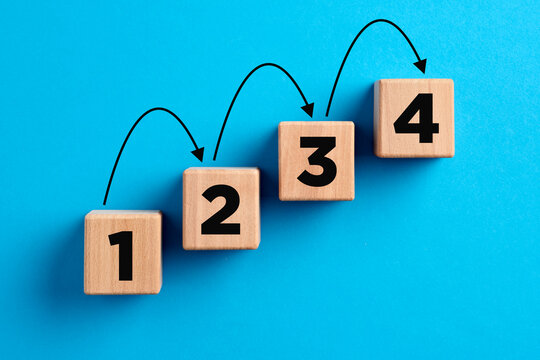 Step by step progress in business planning, career improvement or problem solving concept. Numbers with arrows on wooden cubes.