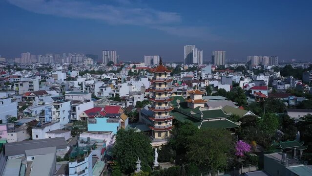 Buddhist temple and prayer tower in urban rooftop setting with view to city skyline on a sunny day with blue sky.
Location is An Phu a district of Ho Chi Minh City, Vietnam. Aerial CCW orbit shot.