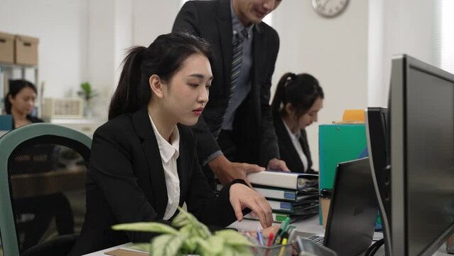slow motion of tired chinese female employee overloaded with more work from her boss in the office. the heap of business assignment gives her headache