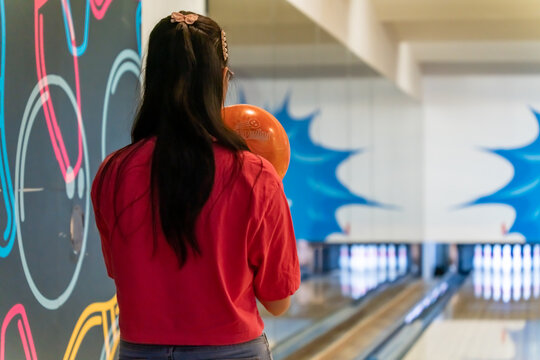 Young asian holding bowling ball, relaxing concept, a woman's hand throws a bowling ball close-up, a woman plays bowling on the background of the playing
