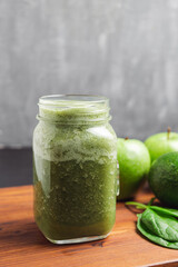 Green smoothie drink blended in a glass jar, avocado, spinach leaves and apples at wooden board