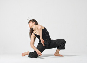 Fototapeta na wymiar Professional female dancer performing in studio at a white wall 