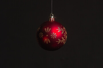 Red Christmas ball on a Christmas tree with a garland on the black background