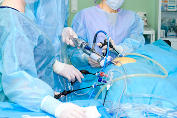 Hands of surgeons in sterile gloves with laparoscopic surgical manipulators during proctologic...