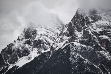 Dreamy mysterious winter landscape with fog and snow covered mountains and clouds in the sky