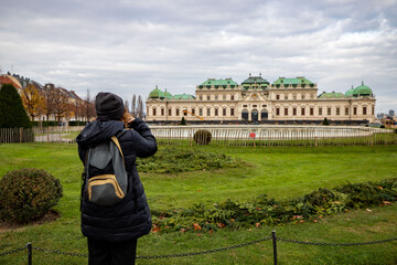 Young girl with camera is taking a photo at Schloss Belvedere in Vienna. Beautiful girl traveling in winter in Vienna.