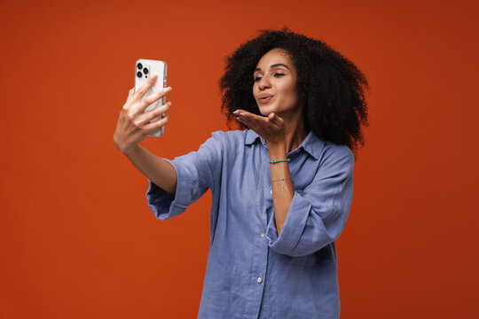 Young woman with curly hair using cellphone for selfie photo