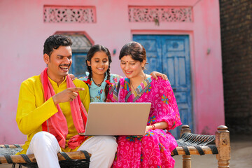 Indian farmer family using laptop at home.