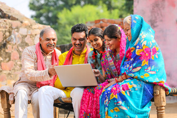 Indian farmer family using laptop at home.