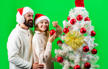 Merry Christmas and Happy new year. Smiling couple in Santa hat decorating christmas tree at home.