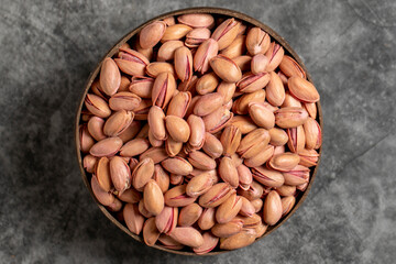Pistachios in bowl on dark background. Shelled pistachios in a coconut bowl. Top view