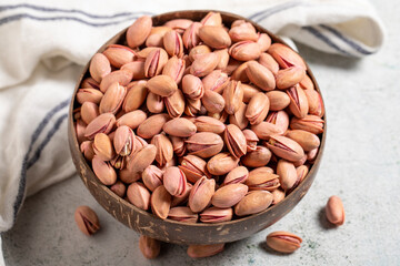 Pistachios in bowl on gray background. Shelled pistachios in a coconut bowl. close up