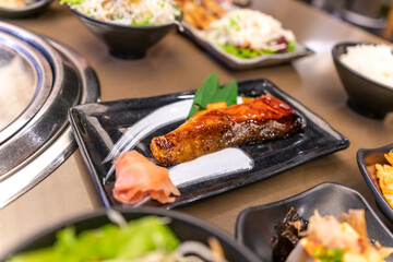 a piece of Canadian salmon cooked in a teriyaki sauce served on a black stone plate at close up view