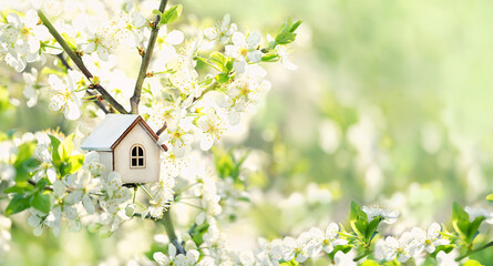 toy house on blossom cherry flowers, spring natural background. concept of mortgage, construction, rental, family and property. eco-home. spring season. template for design - obrazy, fototapety, plakaty