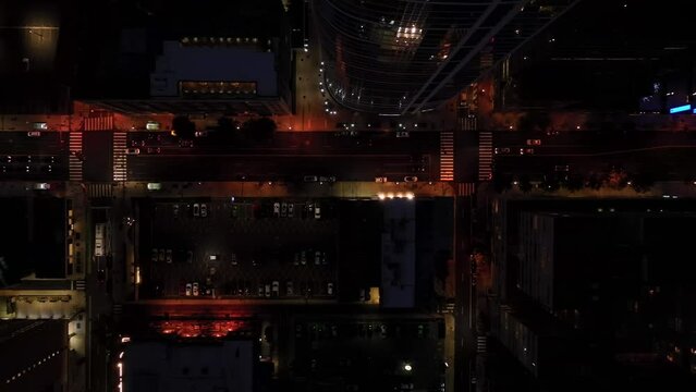 Top down aerial of urban city traffic at night. Skyscraper towers and highrise buildings. Truck shot in darkness.