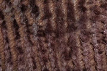 Background from dark brown fur and wool. Combined knitted fur product with inserts of fox wool and fur.