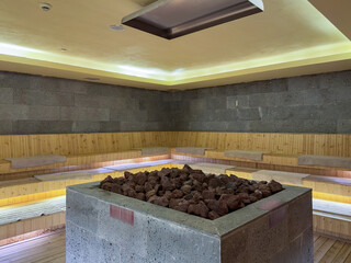 Seat in sauna room. Empty wooden steam room with stone heater.Sauna room for good health. Sauna...