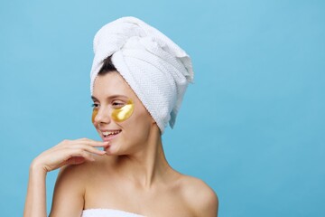 Horizontal photo, a woman with white skin on a blue background with a towel on her head and...