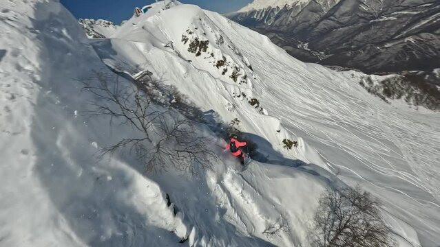 Sportsman skier extreme sport freeride downhill drop snow cornice mountain summit adrenaline race splash aerial view. FPV drone shot male ski professional athlete rider cliff valley sunny 50fps slo-mo