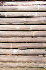 ฺBamboo fence or bamboo brown and yellow wall texture background. Dry bamboo is used to make fences or walls of the house. Build a bridge over a river or across a canal.