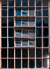 Old factory window texture with sky reflection, London, UK