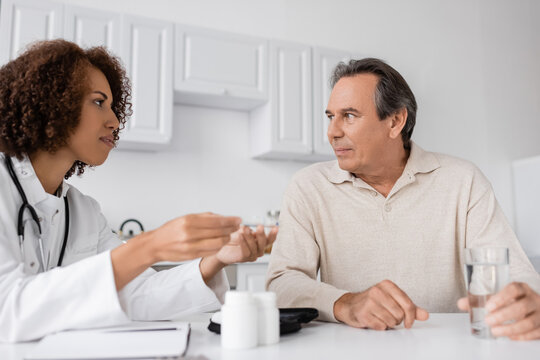 Curly African American Doctor Showing Lancet Pen To Middle Aged Patient With Diabetes