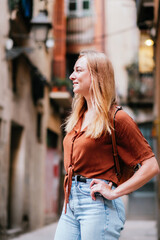 Fototapeta premium side portrait of a young caucasian tourist in the streets of Barcelona old town. She is looking to one side and smiling