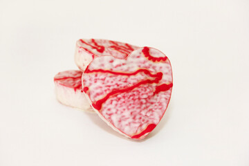 Sweet glazed cookies in the shape of a heart with a red decorative pattern on a white background