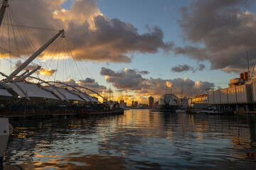 Fototapeta na wymiar GENOA, ITALY, DECEMBER 5, 2022 - View of the Ancient Port of Genoa at sunset with sky covered with clouds, Italy