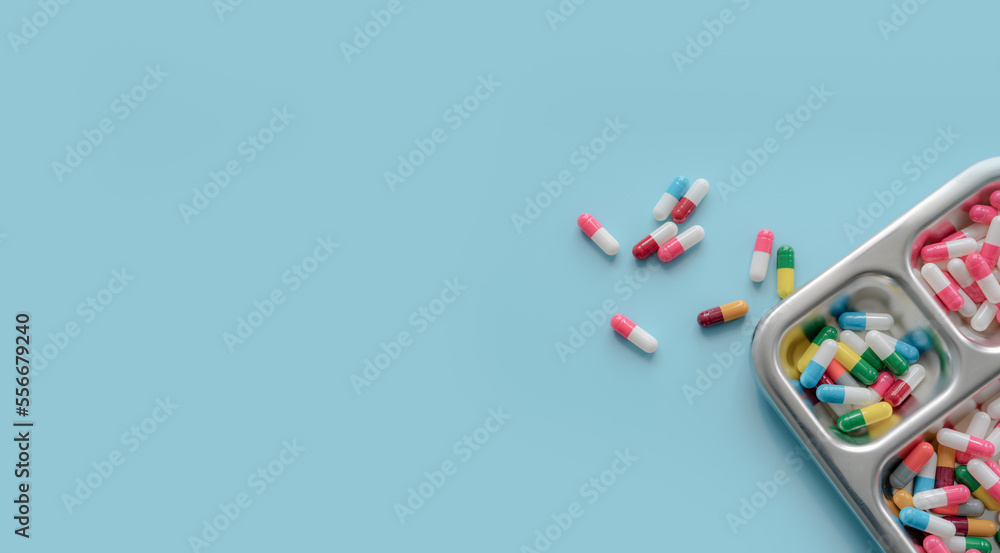 Poster above view of colorful antibiotic capsule pills on a tray and blue background. antibiotic drug resis