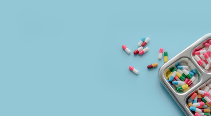 Above view of Colorful antibiotic capsule pills on a tray and blue background. Antibiotic drug...