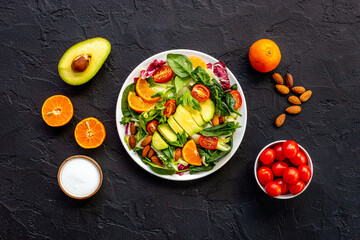 Overhead view of cooking healthy green salad with avocado and tomatoes