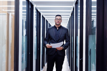 Young businessman standing holding documents inside office. Business concept.