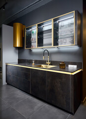 Upscale flat design kitchen with induction black glass hob with cylinder golden extractor hood with...