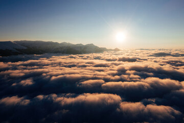 Caucasian mountains above the clouds at the sunset. Cloudscape, aerial view