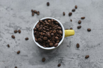 Top view of roasted coffee seeds on yellow mug isolated on gray background