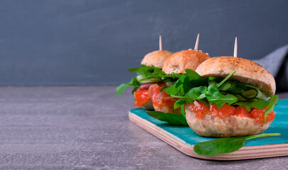 Burgers with salted trout, arugula and cucumber served on grey table. Seafood appetizer. Mockup with copy space