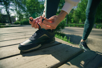 Obraz premium Woman hands to tie their shoes jogging in morning workout at the city, closeup shot