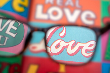 LOVE through glasses. first person looking at the word love in colorful comic style. point of view love Love message written in big letters. love is blind. Point of view through reading glasses