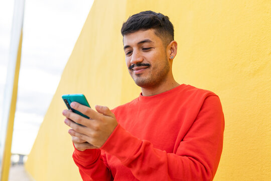 Glad Hispanic man using smartphone on street
