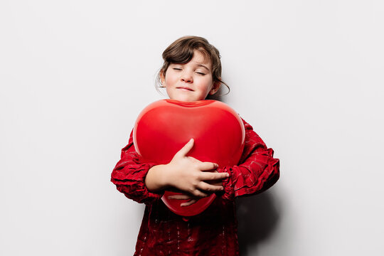 Happy girl hugging heart shaped balloon